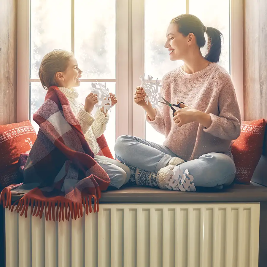 Heating and Cooling Services - mother and daughter watch the snowy day outside from the comfort of their heated home - Vandalia, IL